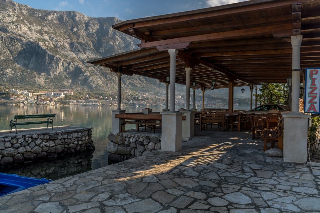 Villa terrace in Prčanj, Montenegro: stonework, wooden canopy, view of the Bay of Kotor and mountains.