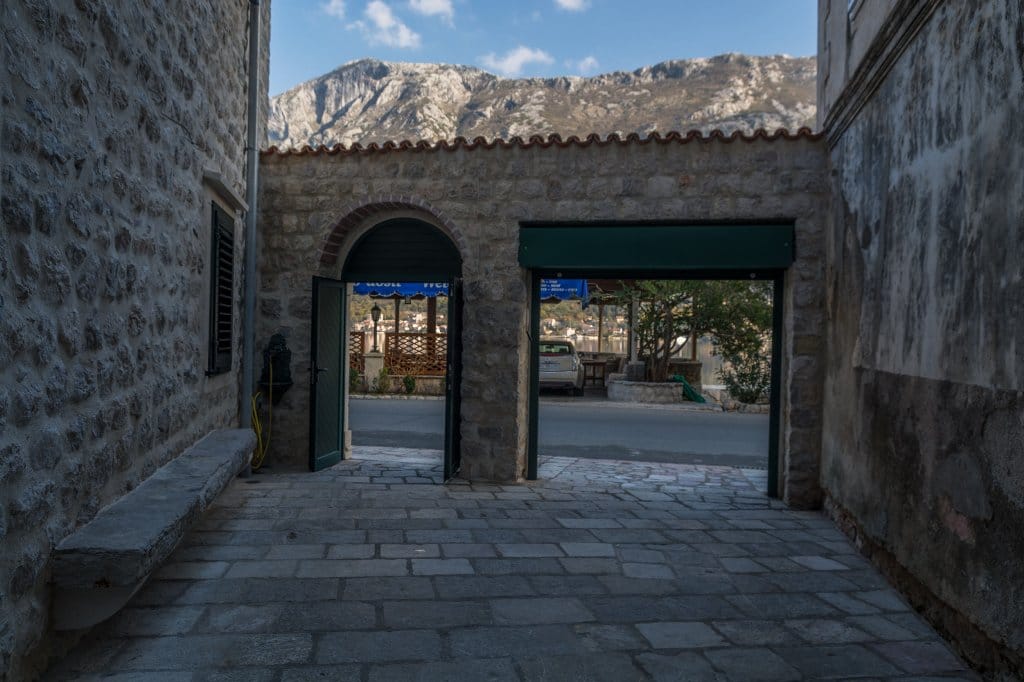 Stone courtyard of a villa in Prčanj, Montenegro, with mountain views and access to the waterfront through an old arch.