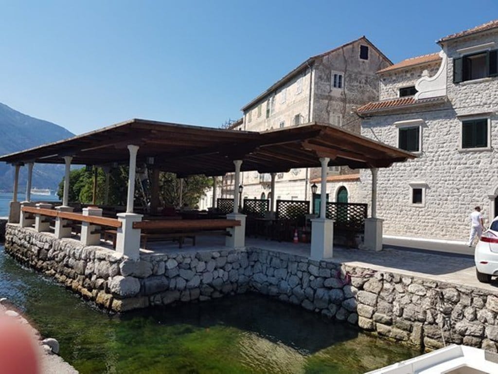 Villa terrace by the sea in Prčanj, Montenegro: stone finish, wooden canopy, and views of the Bay of Kotor.