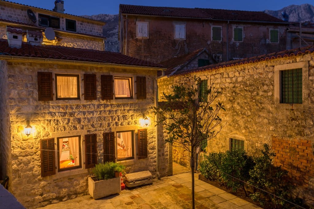 Evening view of a stone villa in Prčanj, Montenegro: traditional architecture, cozy lighting, and an inner courtyard.