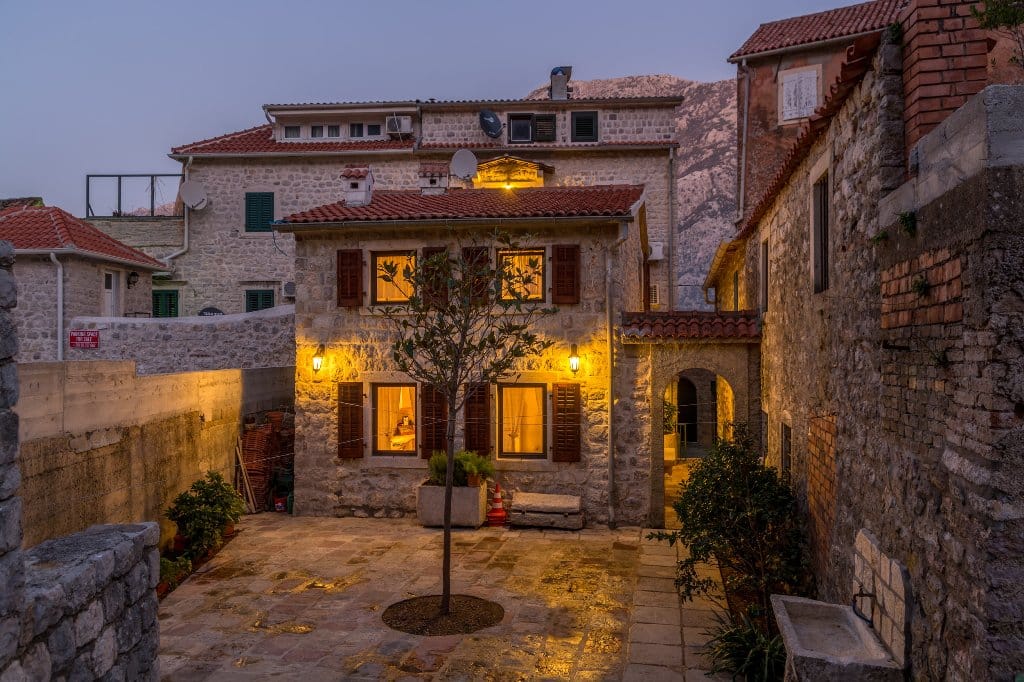Evening view of a stone villa in Prčanj, Montenegro: a cozy courtyard, authentic finishes, and warm lighting.