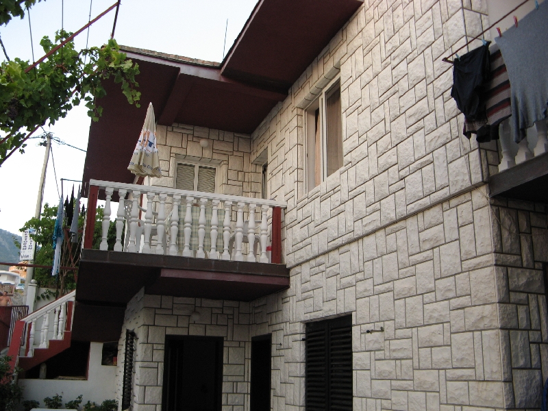 Two-story house in Shushan, Montenegro: light stone facade, balcony with balustrade, and a Mediterranean-style terrace