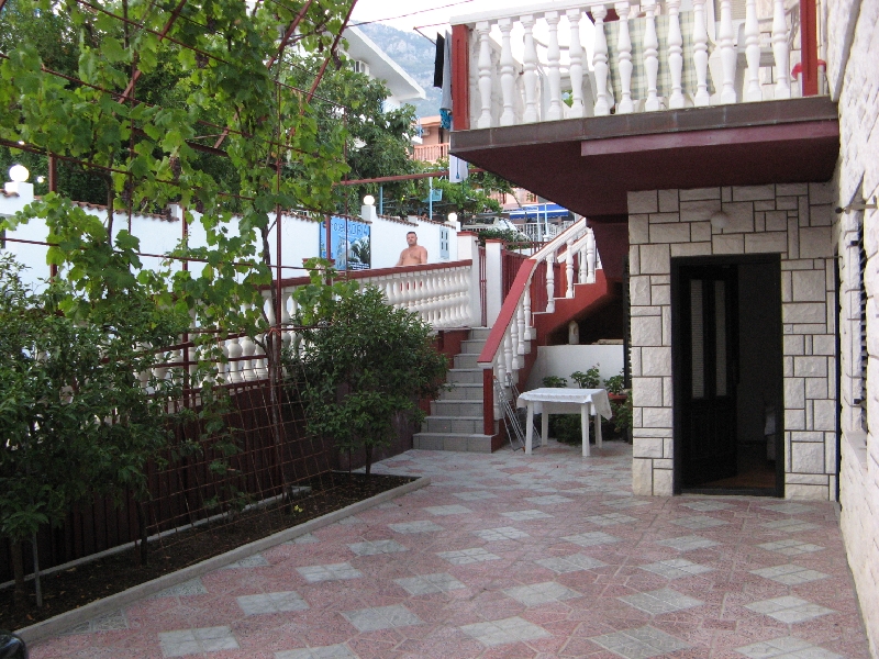Courtyard of a house in Shushan, Montenegro: tiled terrace, stone facade finish, staircase, and vineyard.