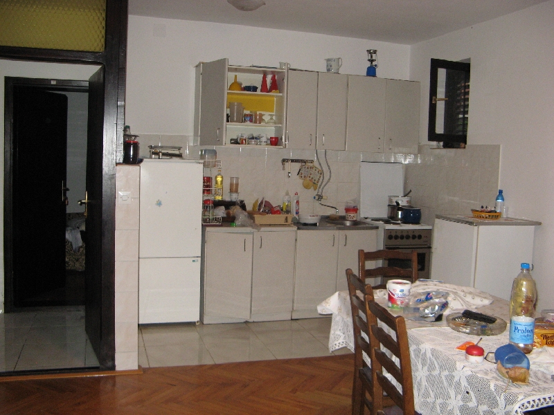 Kitchen in a house in Shushan, Montenegro: light-colored cabinetry, dining table, appliances, and parquet flooring in the interior.