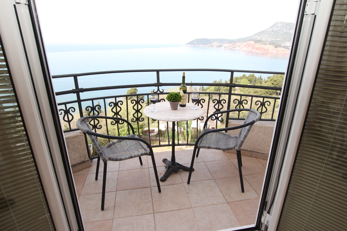 Balcony with panoramic sea view in building No. 988, Sutomore, Montenegro: wicker furniture and a small table for relaxing.