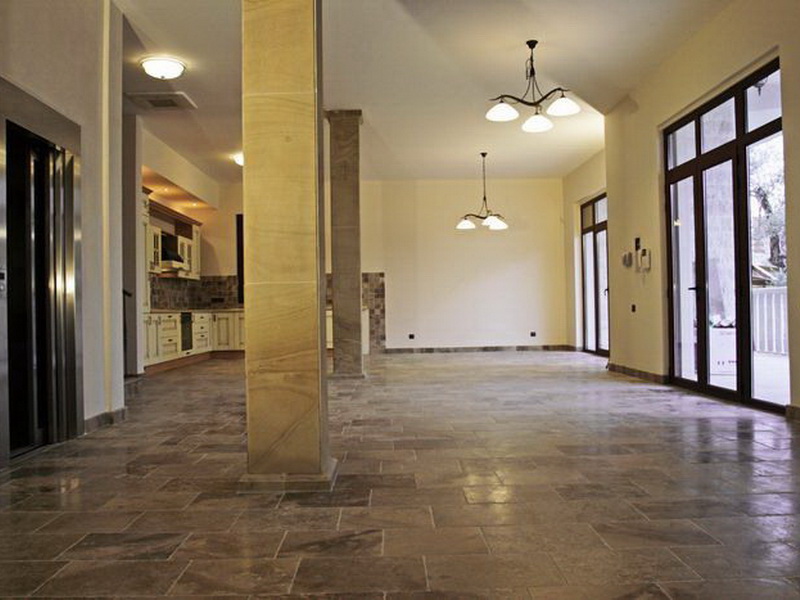 Spacious living room with stone floor, columns, and kitchen in a villa in Petrovac, Montenegro.