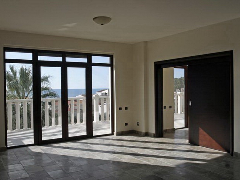Bright living room with panoramic windows and sea views in a villa, Petrovac, Montenegro: stone floor and sliding doors.