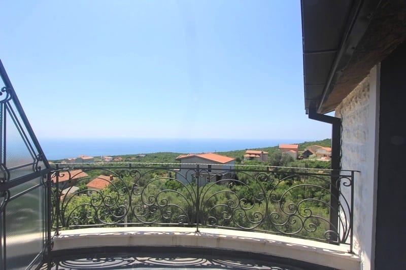 Balcony with wrought-iron railing and panoramic views of the sea and mountains in a house, Krymovitsa village, Montenegro.
