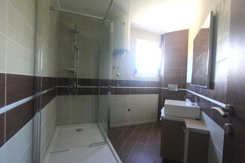 Modern bathroom with a shower cabin in a house, Krymovitsa, Montenegro: tiles, vanity with sink, and mirror.