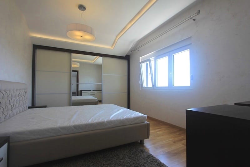 Bright bedroom with a double bed and a built-in wardrobe in a house, Krymovitsa village, Montenegro. Modern interior.