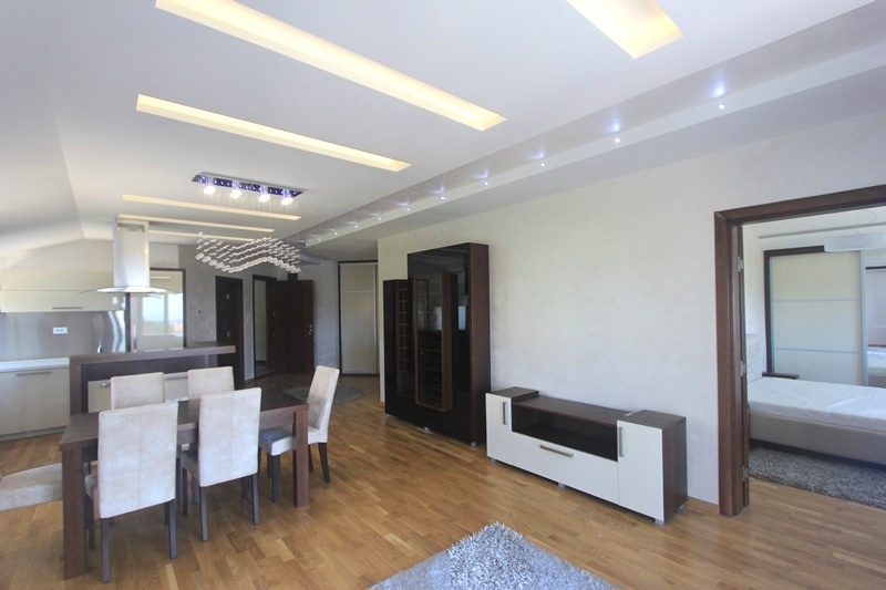 Modern living room with dining area and kitchen in a house in Krimovice, Montenegro: parquet flooring, stylish furniture, and lighting.
