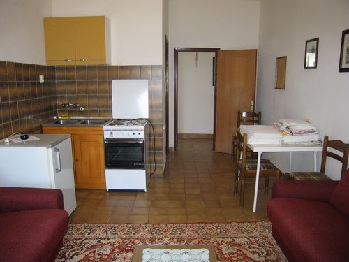 Kitchen-living room in a house in Bečići, Montenegro: kitchen set, stove, dining table, and soft furniture.