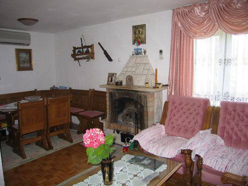 Living room with a fireplace, wooden furniture, and a seating area in a house for sale in Bečići, Montenegro.
