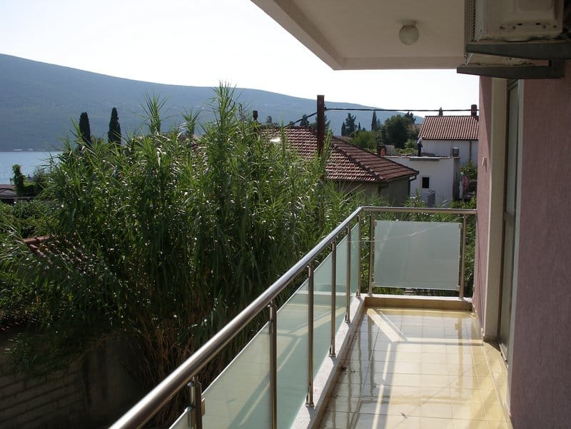 Balcony with tiled floor and glass railing in an apartment in Baošići, Montenegro, with sea and mountain views.