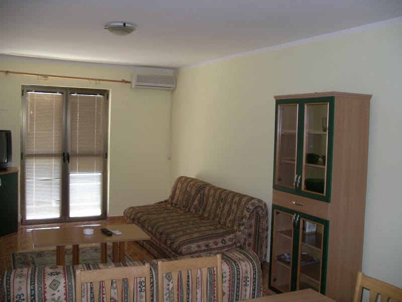 Living room in an apartment in Baošići, Montenegro: soft seating, display cabinet, coffee table, and access to the balcony.