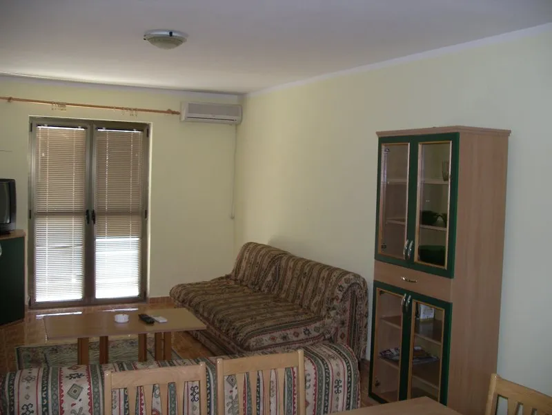 Living room with patterned sofa, wooden cabinet, coffee table, and window with blinds.