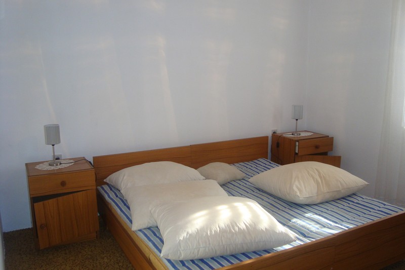 Bright bedroom with a double bed and wooden nightstands in a house for sale, Dobrota, Montenegro.