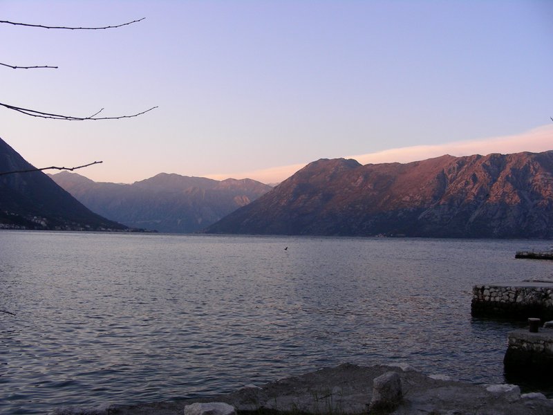Panoramic view of the Bay of Kotor and mountains from a house in Dobrota, Montenegro: seascape with a stone pier at sunset.