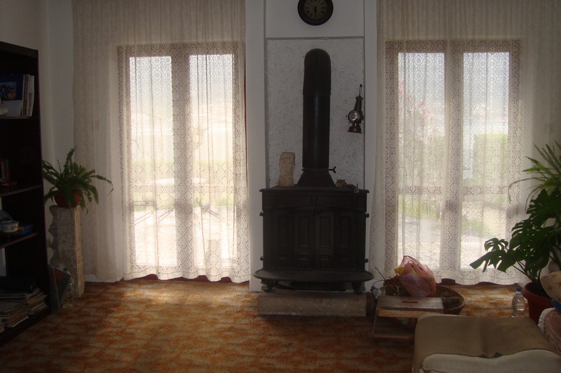 Living room with a fireplace and panoramic windows in a house for sale, Dobrota, Montenegro.
