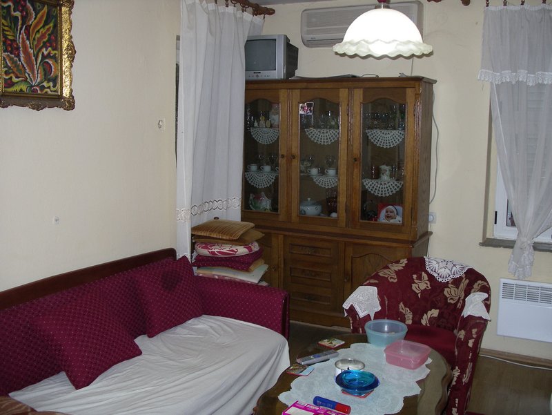 Living room in a house in Petrovac, Montenegro: a classic wooden sideboard, a sofa, an armchair, and a coffee table.