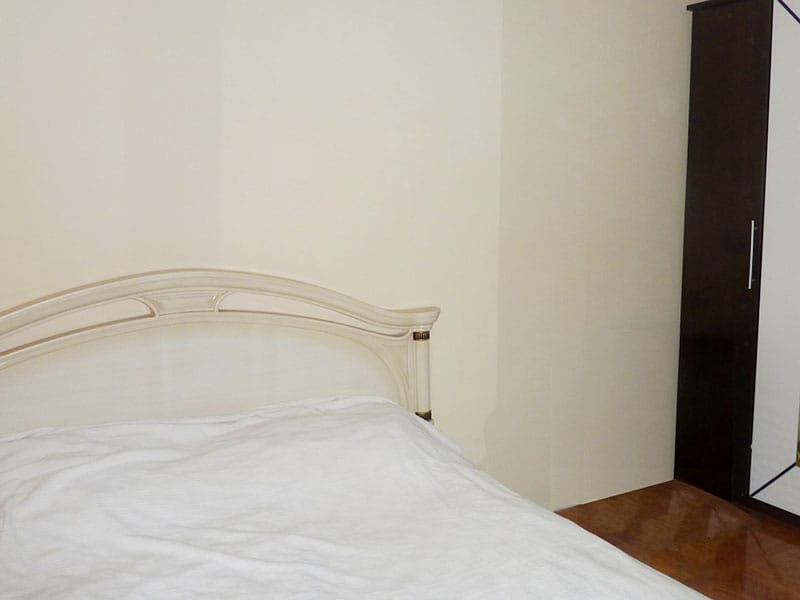 Bedroom in an apartment in Sveti Stefan, Montenegro: a double bed with a white headboard and a wardrobe in the interior.