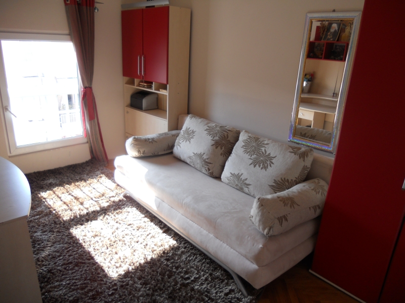 Cozy living room with a sofa, rug, and wardrobe in an apartment for sale in Budva, Montenegro.