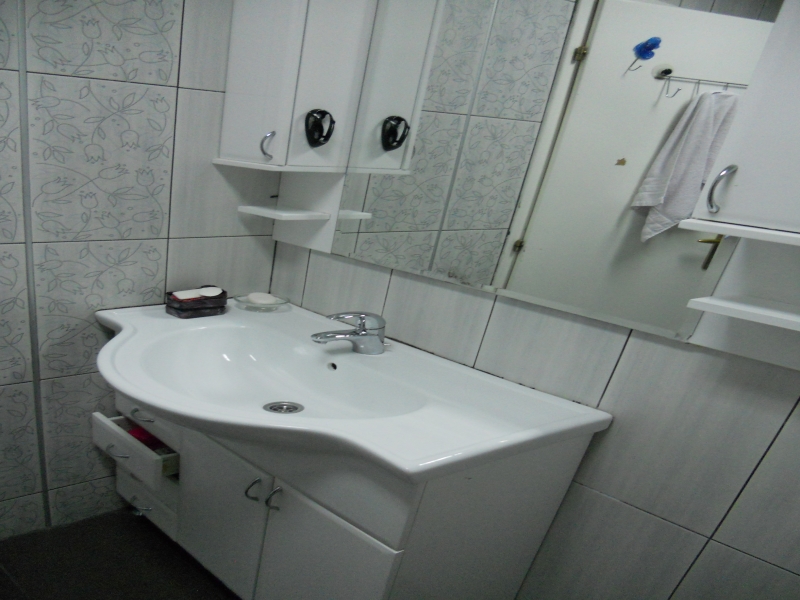 Bathroom in an apartment in Budva, Montenegro: white vanity with sink, mirror, and floral-patterned tile.