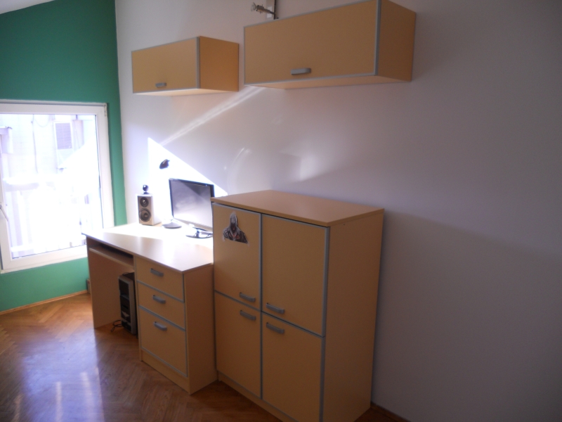 Work area in the bedroom of an apartment in Budva, Montenegro: desk, cabinets, computer, and parquet flooring.