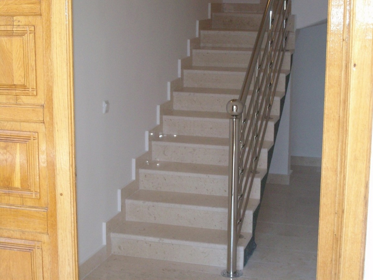 Staircase of light stone with metal railings in the interior of a villa in Bar, Montenegro.