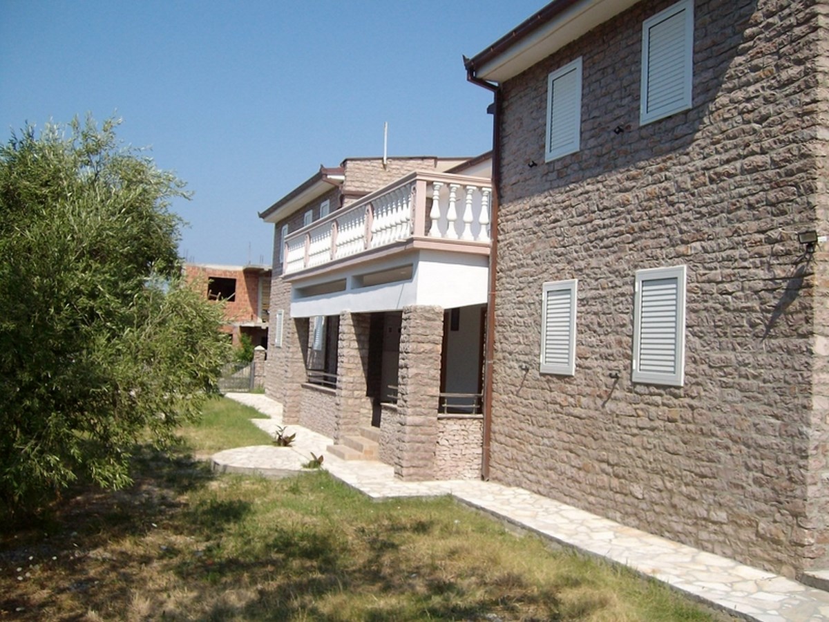 Two-story natural stone villa with a balcony and terrace in Bar, Montenegro. Front view of the house.
