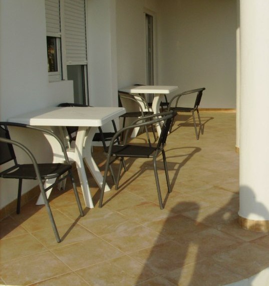 Spacious terrace with plastic furniture in a house in Shushan, Montenegro: tiled floor and light-colored facade finish.