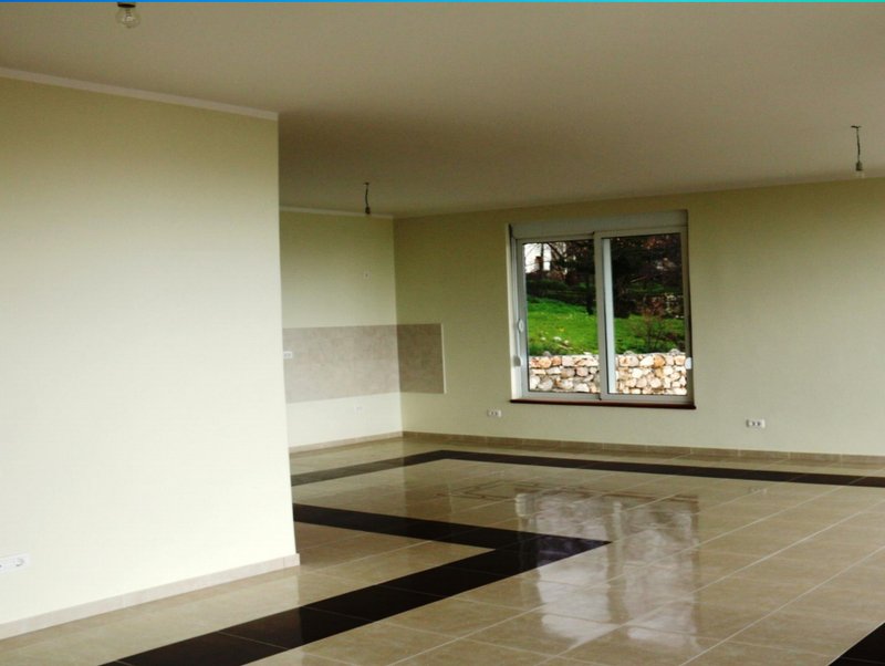 Spacious living room with glossy tiled floor in a house in Shushan, Montenegro, garden view through a panoramic window.