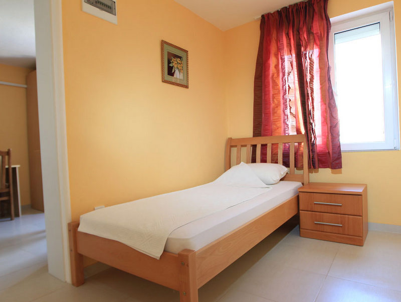 Cozy bedroom with a single bed in a hotel in Budva, Montenegro: light finishes, wooden furniture, and bright curtains.
