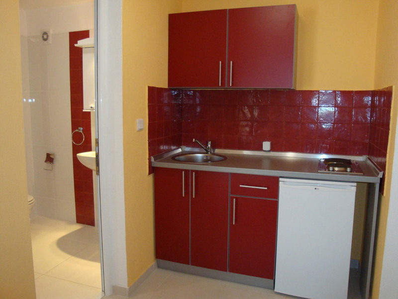 Compact kitchen with red fronts and an en-suite bathroom in a hotel in Budva, Montenegro.