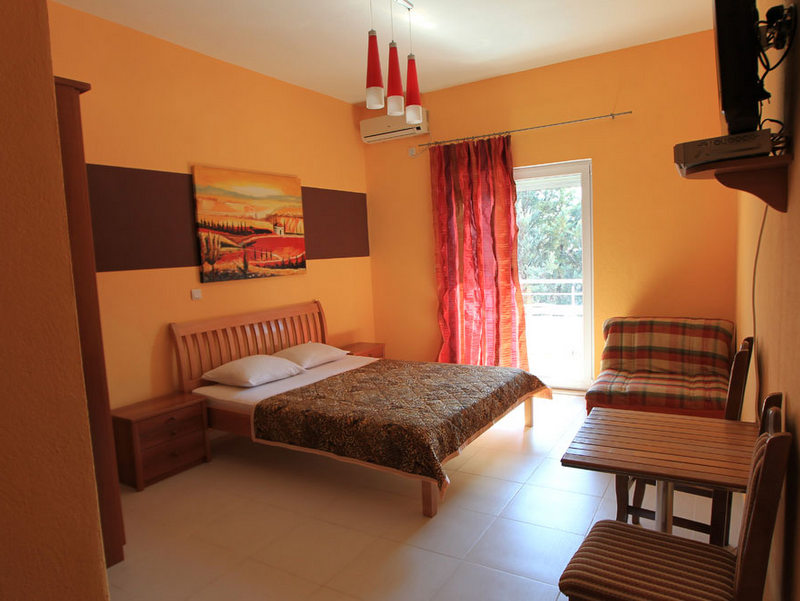 Hotel bedroom in Budva, Montenegro: double bed, wooden furniture, bright interior, and access to the balcony.