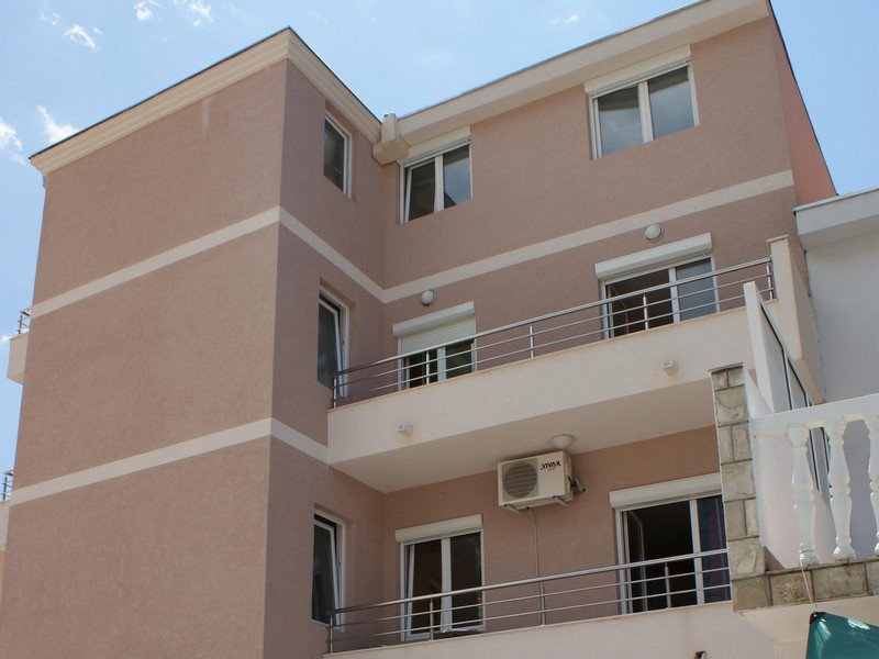 Facade of a modern three-story hotel in Budva, Montenegro, with balconies, panoramic windows, and exterior wall finishes.