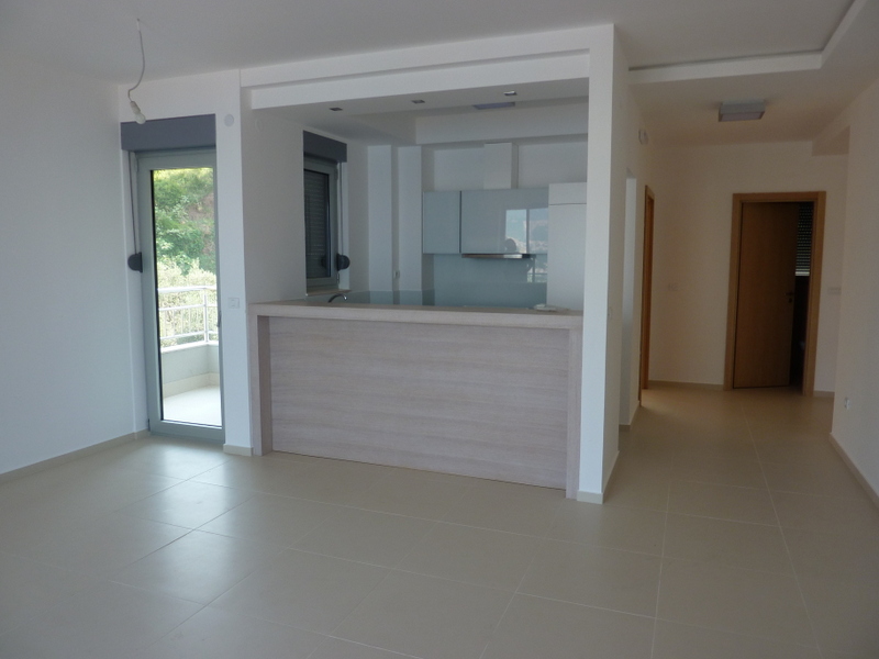 Modern living room with kitchen and bar counter in an apartment for sale, Pržno, Montenegro. Bright interior with a terrace.