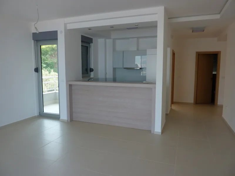 Modern kitchen with a light wood island and blue cabinets, door leading to a balcony visible.