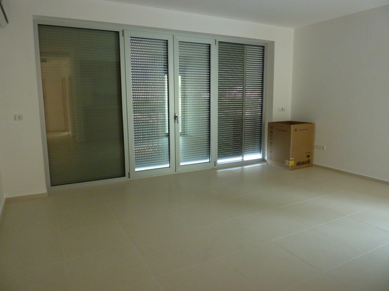 Bright living room with panoramic windows and roller blinds in a new apartment in Pržno, Montenegro. Porcelain stoneware flooring.