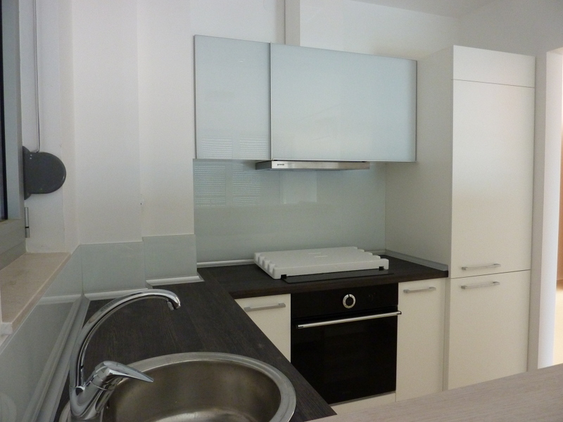 Modern kitchen in an apartment in Pržno, Montenegro: white fronts, dark countertop, built-in appliances, and sink.