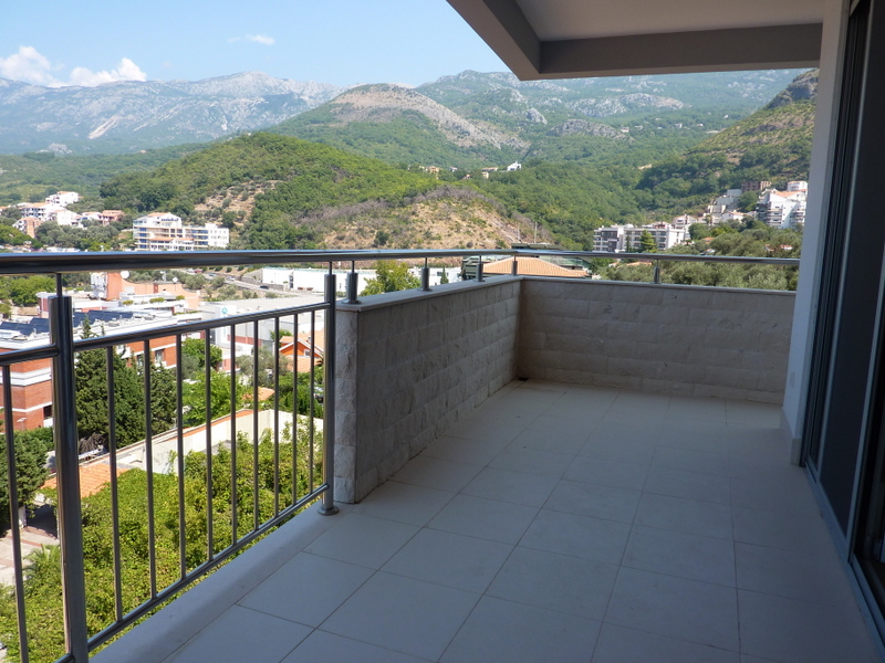 Spacious balcony with stone finishes and mountain views in an apartment in Pržno, Montenegro. Modern steel railing.