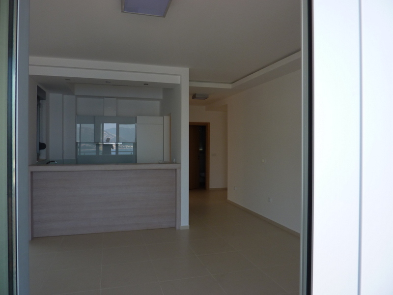 Modern living room with kitchen and bar counter in an apartment in Pržno, Montenegro, with a sea view from the window.