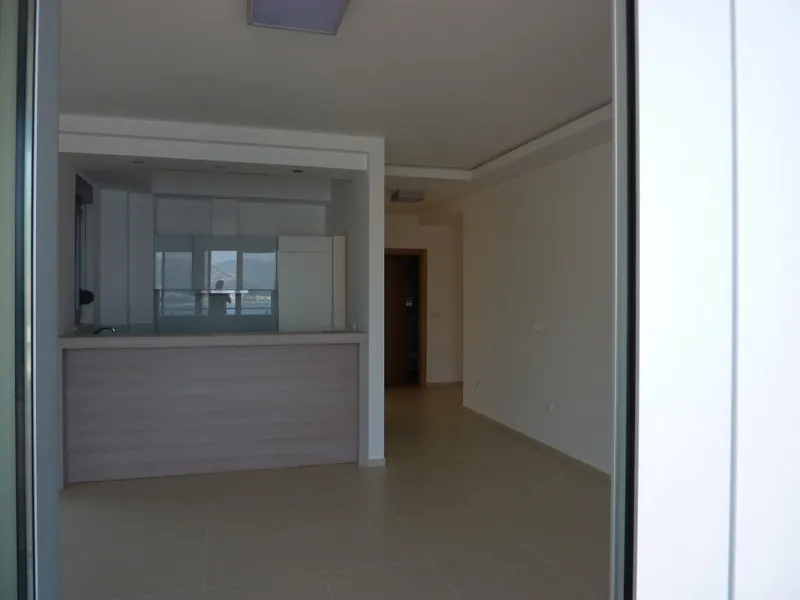 Empty room featuring a light wood kitchen bar counter and white cabinetry near a window with a water view.