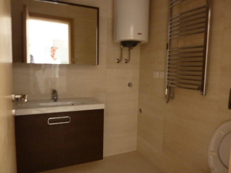 Modern bathroom in an apartment in Pržno, Montenegro: vanity with sink, water heater, and towel warmer.