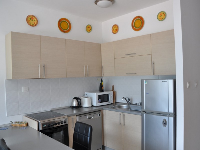 Bright kitchen in an apartment in Bečići, Montenegro: built-in appliances, beige cabinet fronts, and wall decor.