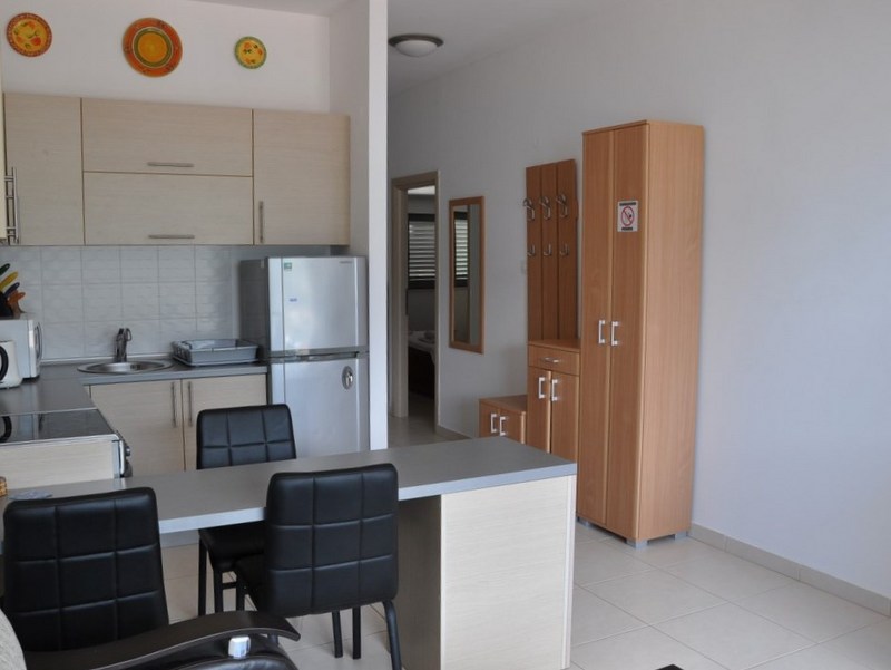 Studio kitchen with dining area and light-colored furniture in an apartment in Bečići, Montenegro. Modern interior with appliances.