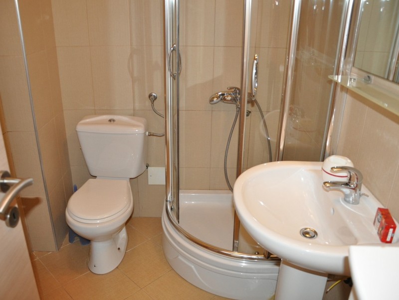 Bathroom in an apartment in Bečići, Montenegro: shower cabin, white sanitary ware, and beige tiles in the interior.