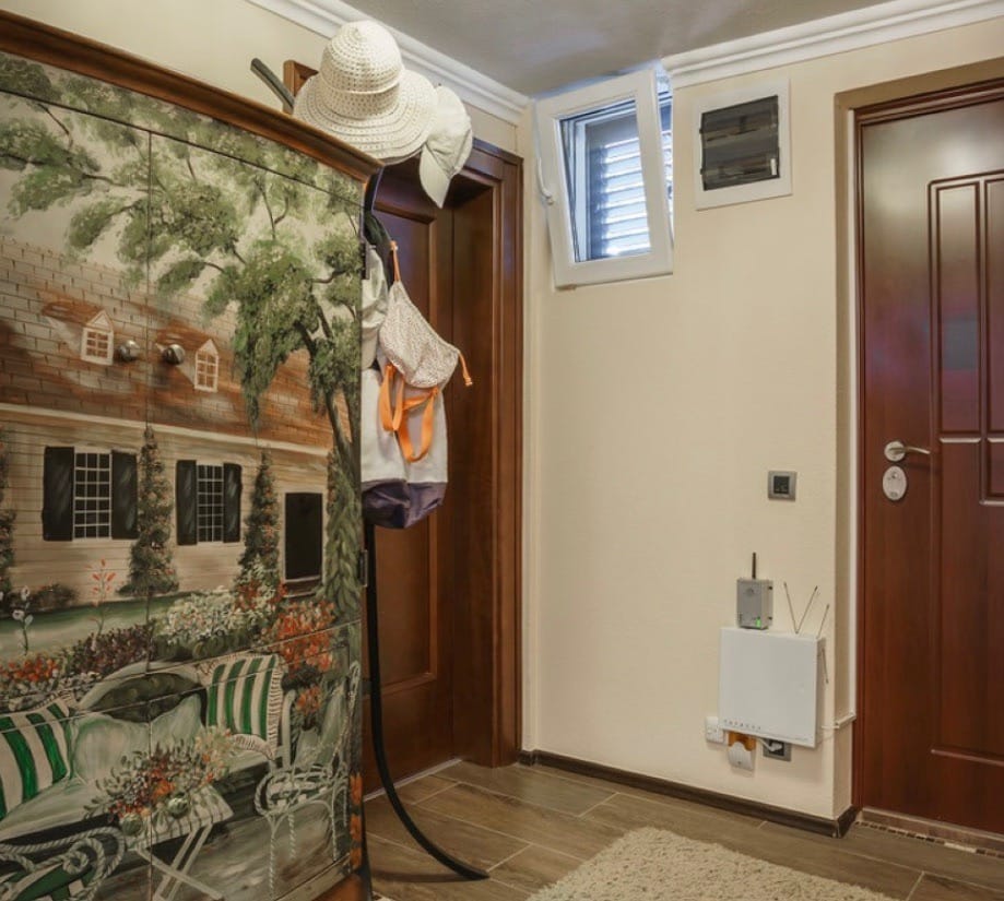 Villa hallway in Stoliv, Montenegro: a painted cabinet, wooden doors, and tiled floor.