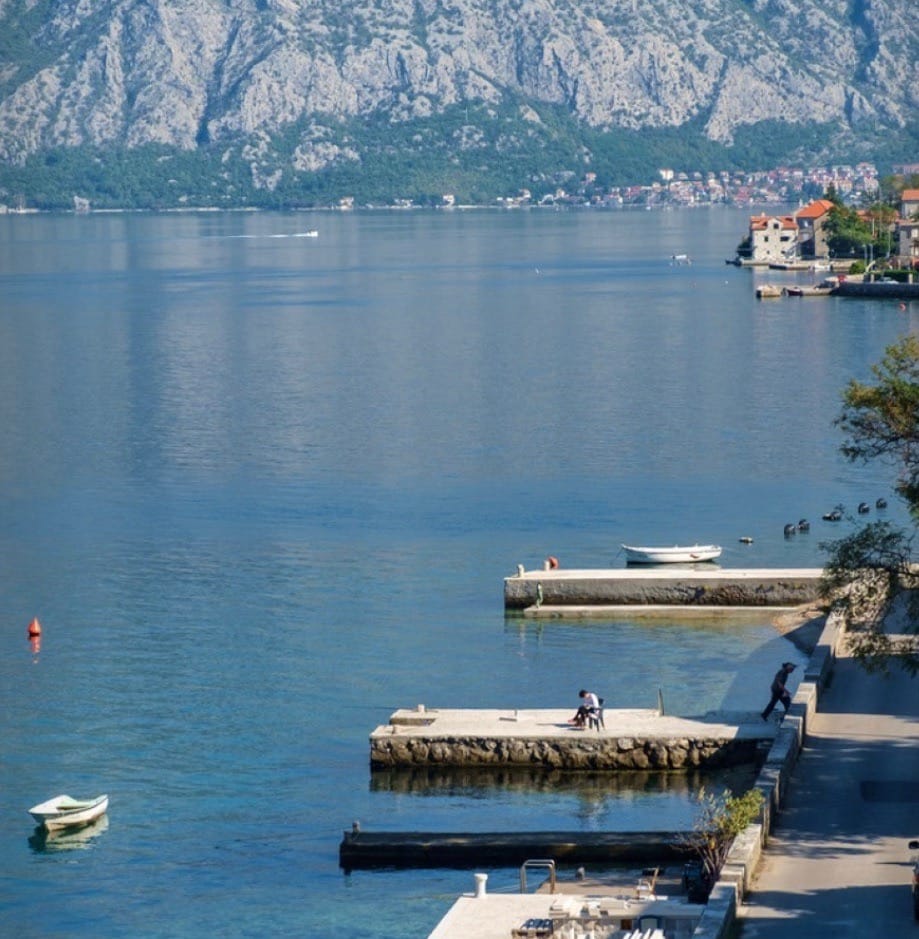 View of the Bay of Kotor and mountains from the villa terrace in Stoliv, Montenegro: piers, boats, and seascape.