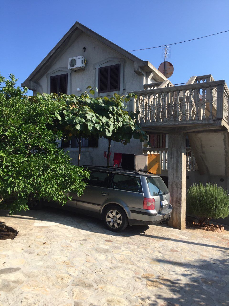 Two-story house with a stone staircase and parking in the yard, Krimovica, Montenegro. View of the facade of a private house.